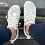 Light-colored barefoot sneakers worn outdoors on a wooden bench