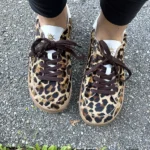 Leopard-print barefoot sneakers with wide toe box, worn with black leggings on pavement.