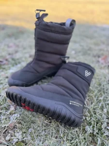 Black insulated kids’ barefoot winter boots photographed on frosty grass.