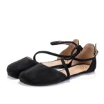 Black ballet flats with ankle strap, studio background