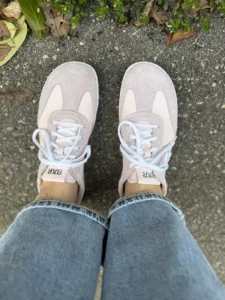 Light pink barefoot sneakers worn outdoors, top view